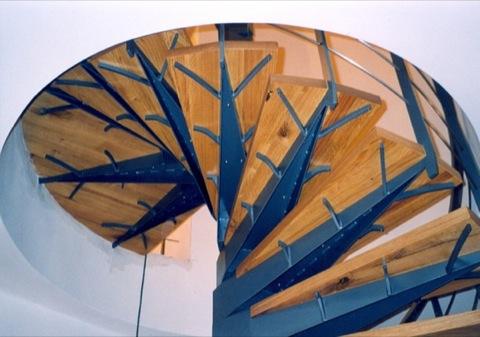 Underside of a spiral staircase with wooden treads on steel brackets