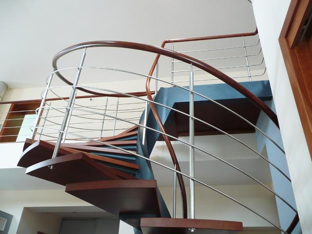 Open spiral staircase with a dark wood handrail and stainless steel bars